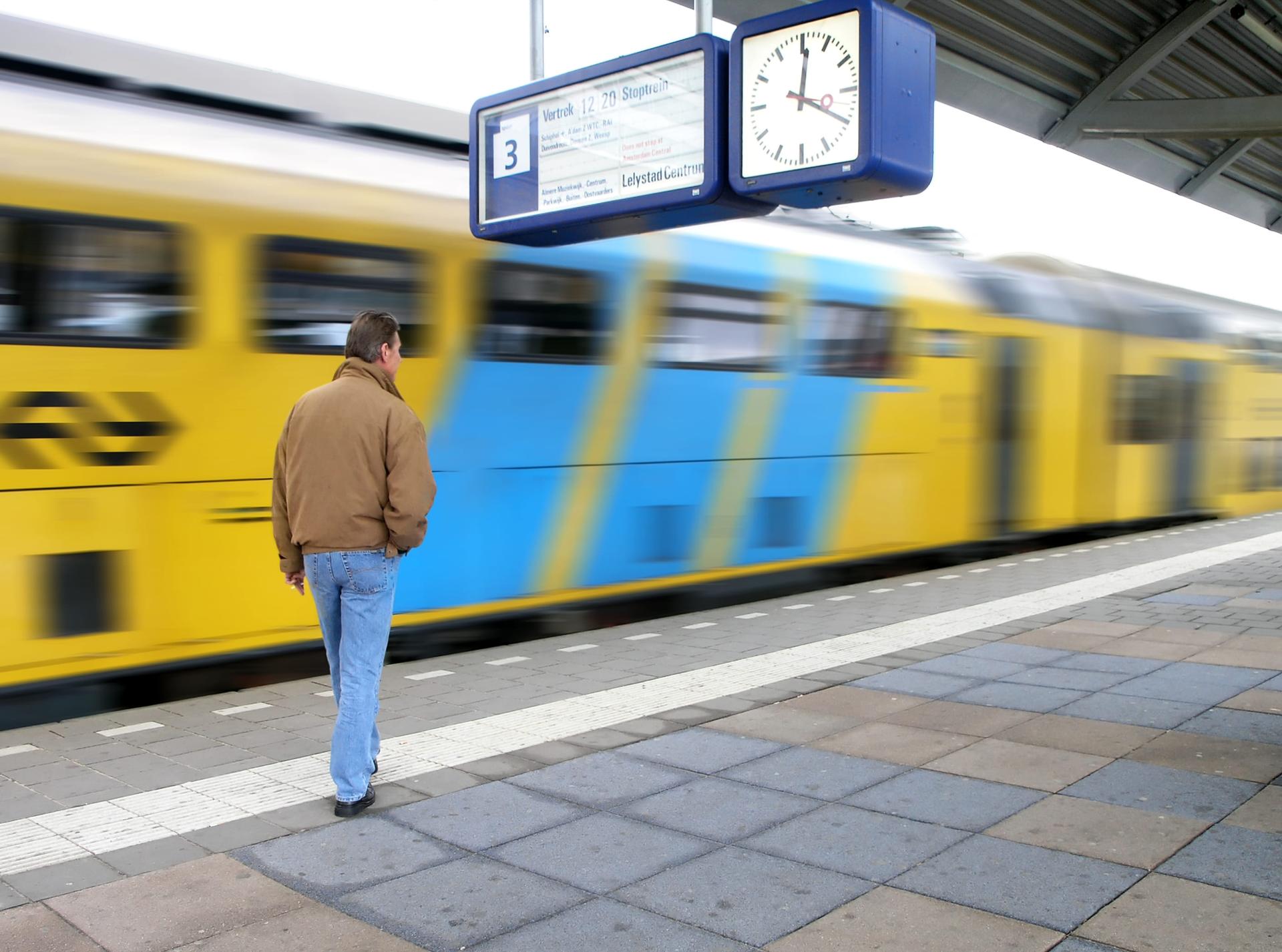 Man staat op het perron terwijl er een NS-trein passeert.