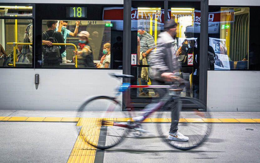 Foto van een metro. Daarvoor beweegt een man die een fiets meeneemt.